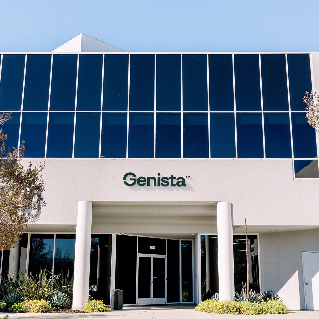 Modern Genista building with blue solar panels and white facade entrance