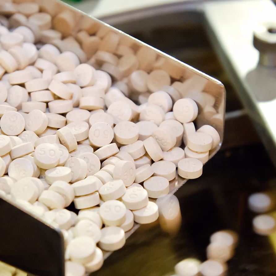 White round pills and capsules displayed in containers at pharmaceutical facility