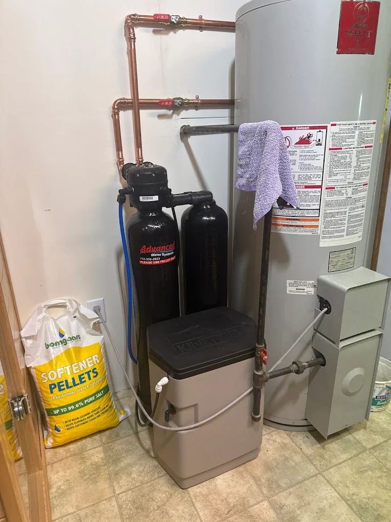 Compact water softener installed beside a residential water heater