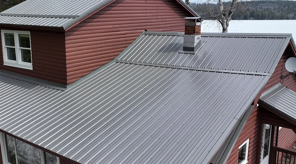 Screw-down metal roofing installed on a residential building showing exposed fastener panels.