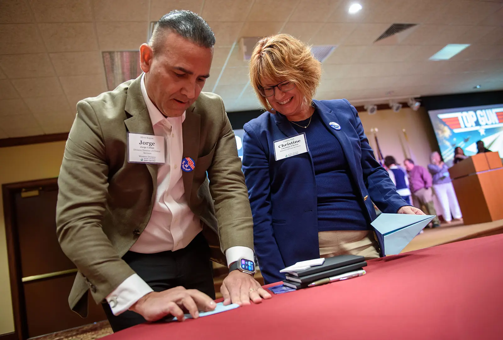 Summit attendees launch paper airplanes past a red velvet rope