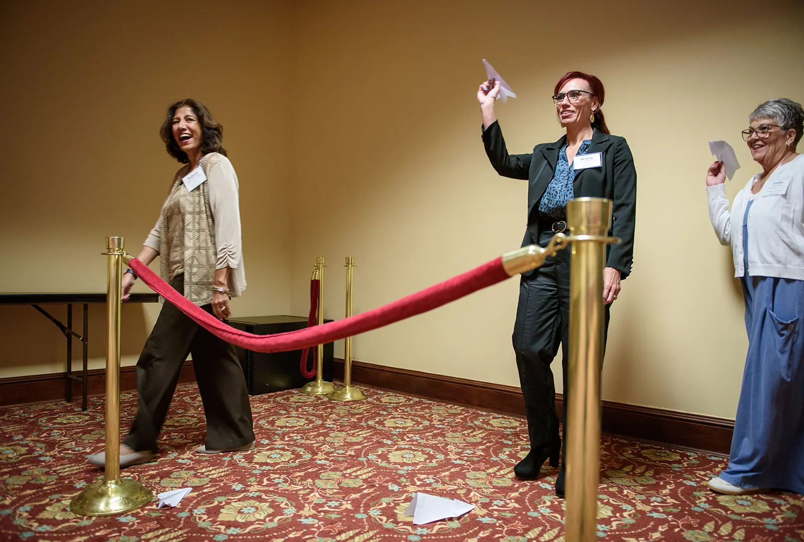 An attendee in a tiara throws a paper airplane in front of the Top Gun-themed stage