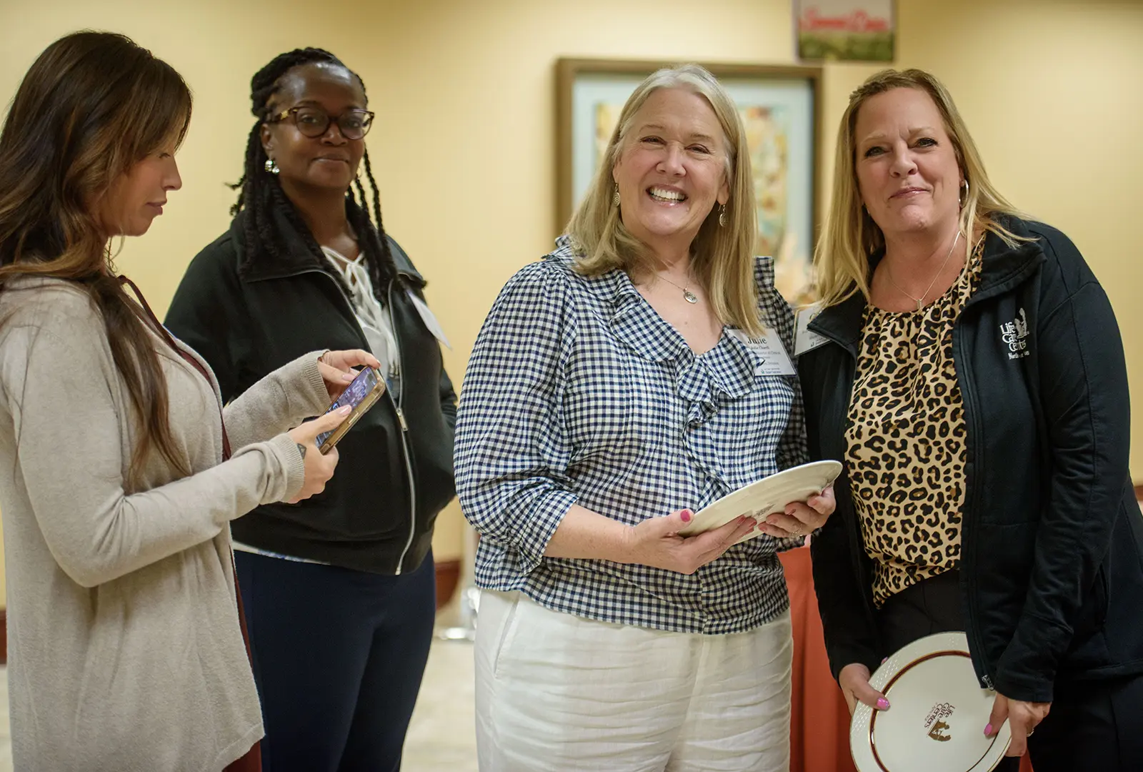 Attendees smile while holding Life Care Centers commemorative plates