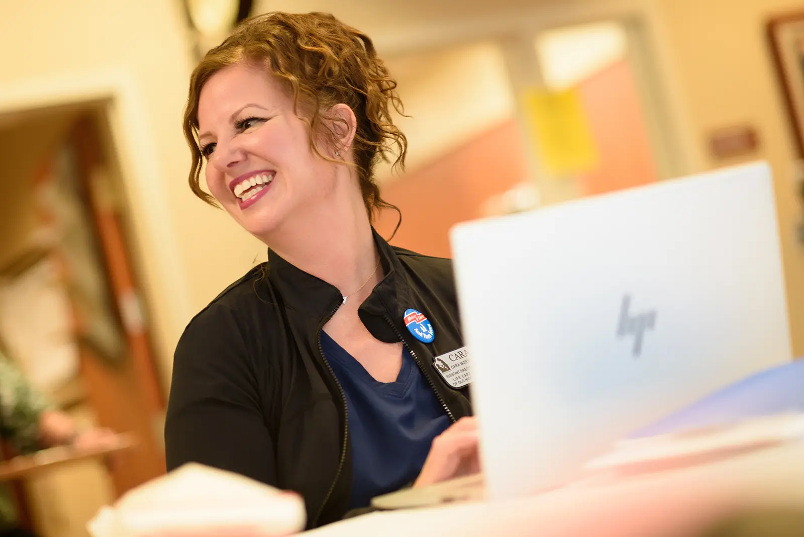 A smiling associate works at a laptop