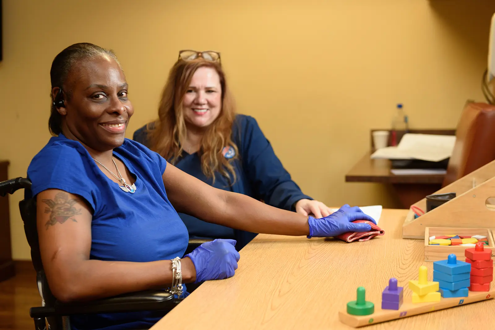 A therapist works with a smiling resident on a therapy activity