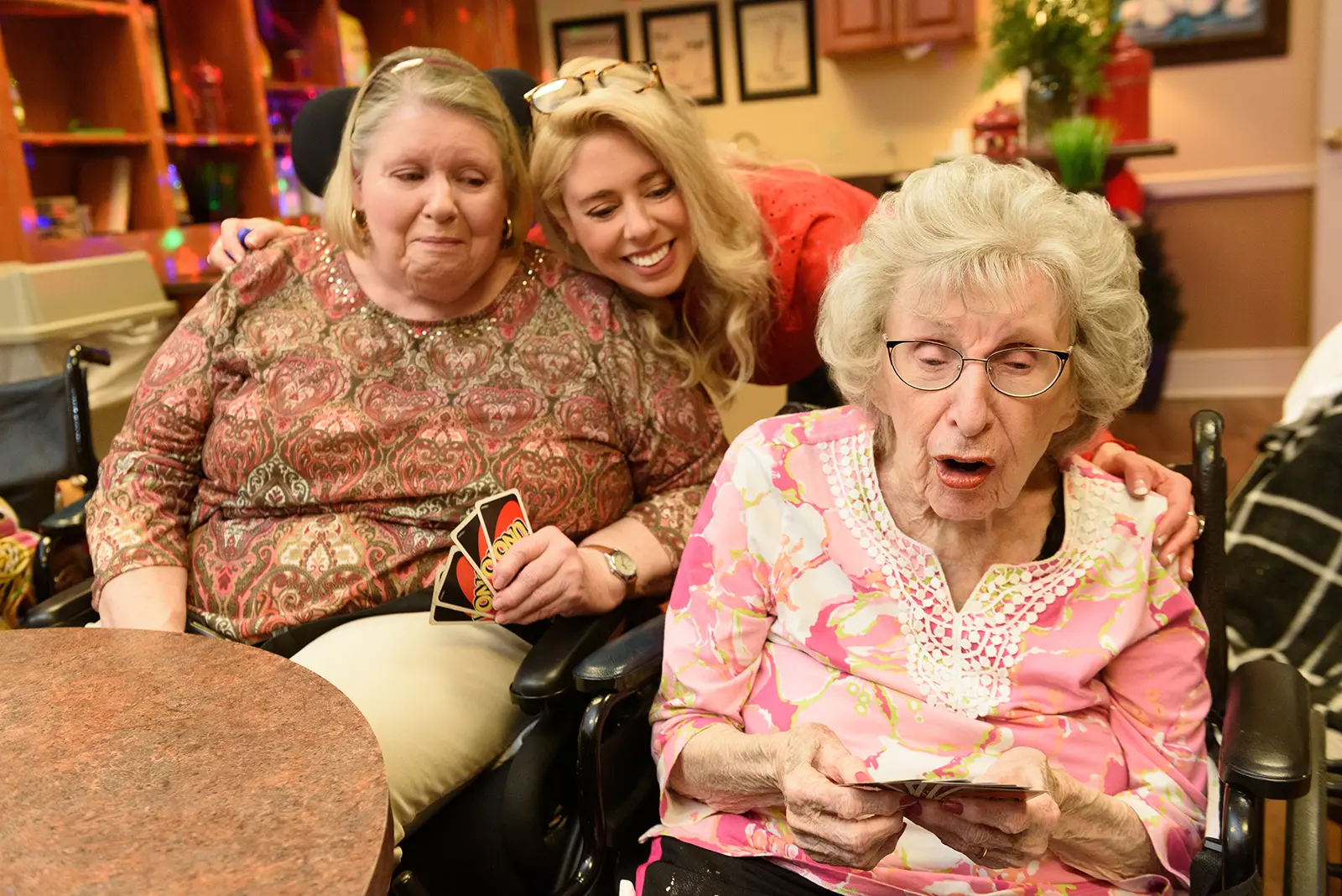 An associate hugs two residents during a card game