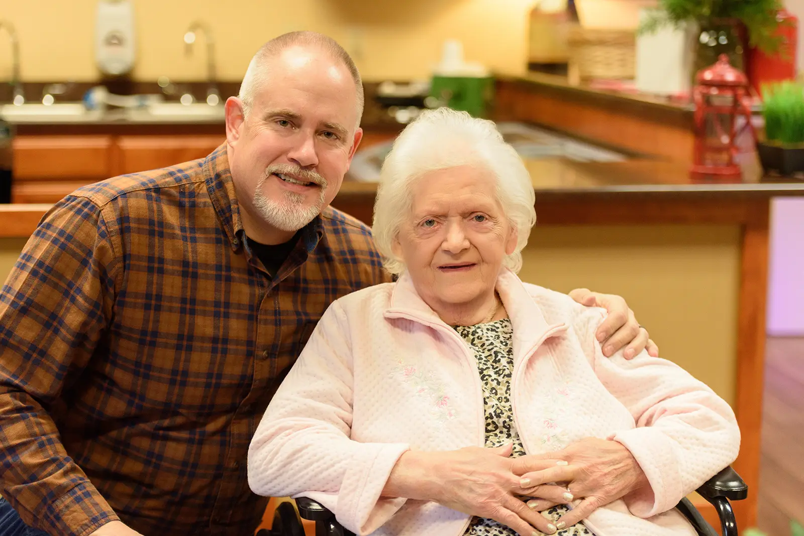 A visitor sits with his arm around a resident