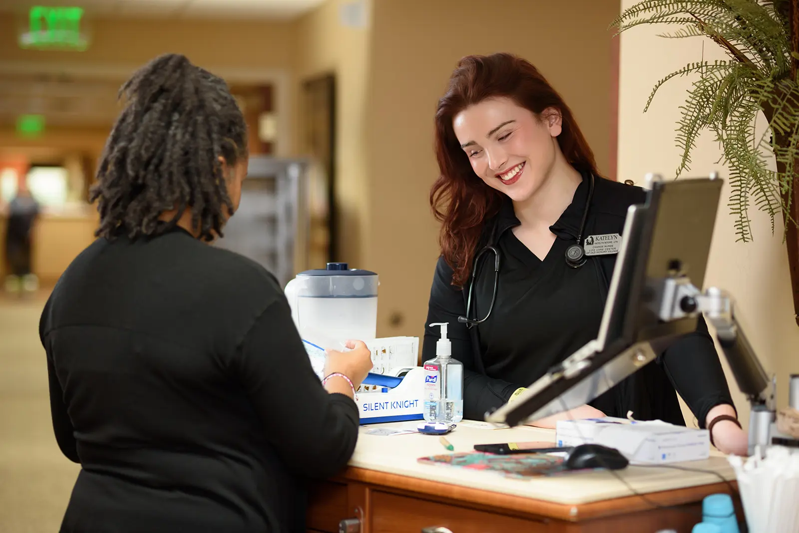 An associate greets a visitor at the front desk
