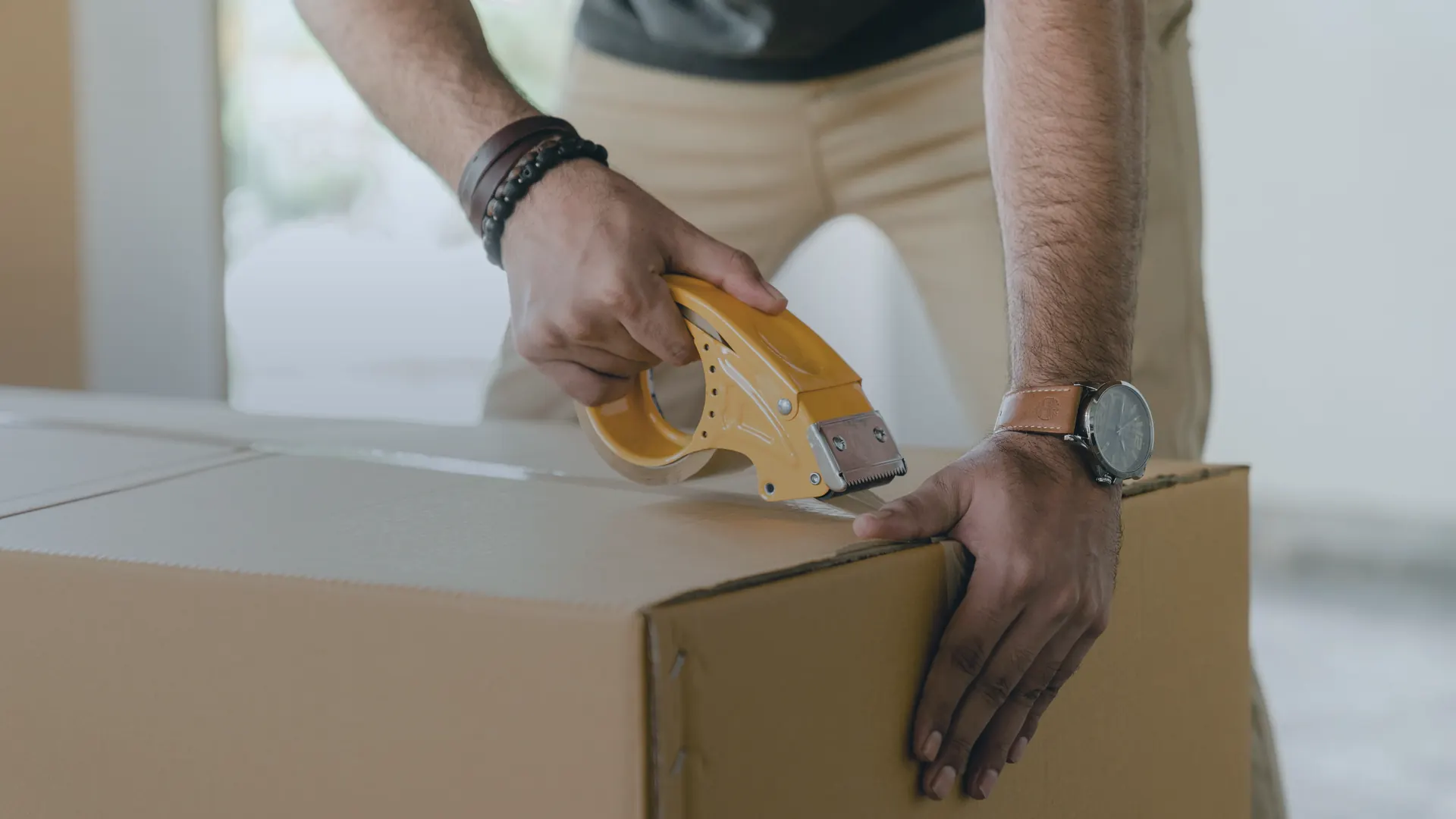 Hands taping a shipping box, a reminder that fulfillment costs shape contribution margin after ads
