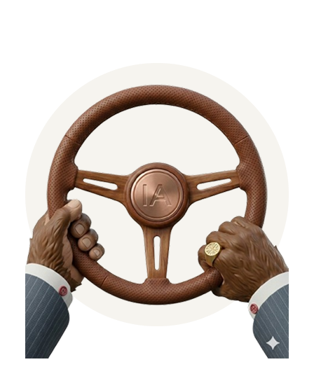 Monkey Hands wearing a suit holding a luxury steering wheel with IA initials in the center.
