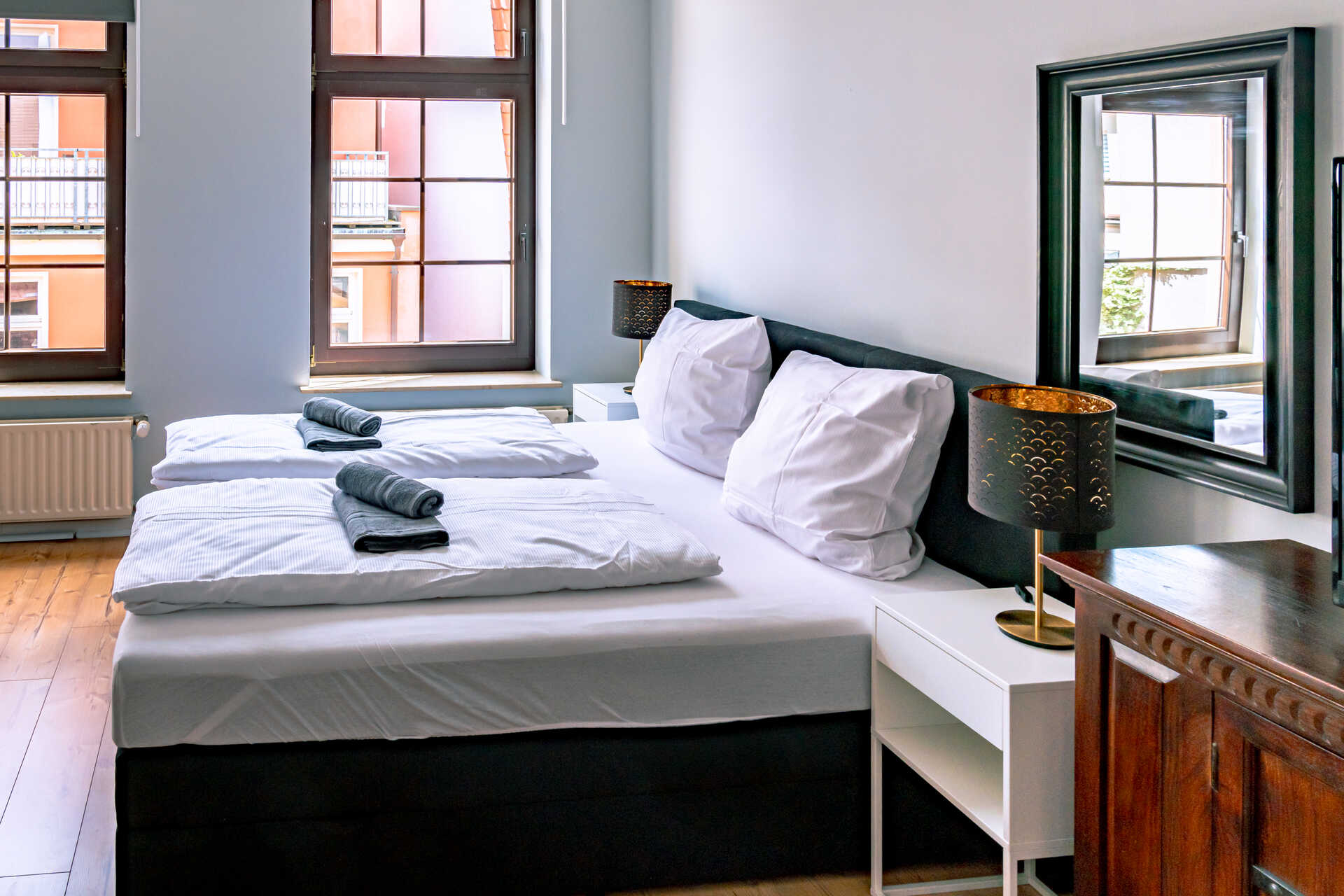 Doppelbett mit grossen Fenstern im Hintergrund