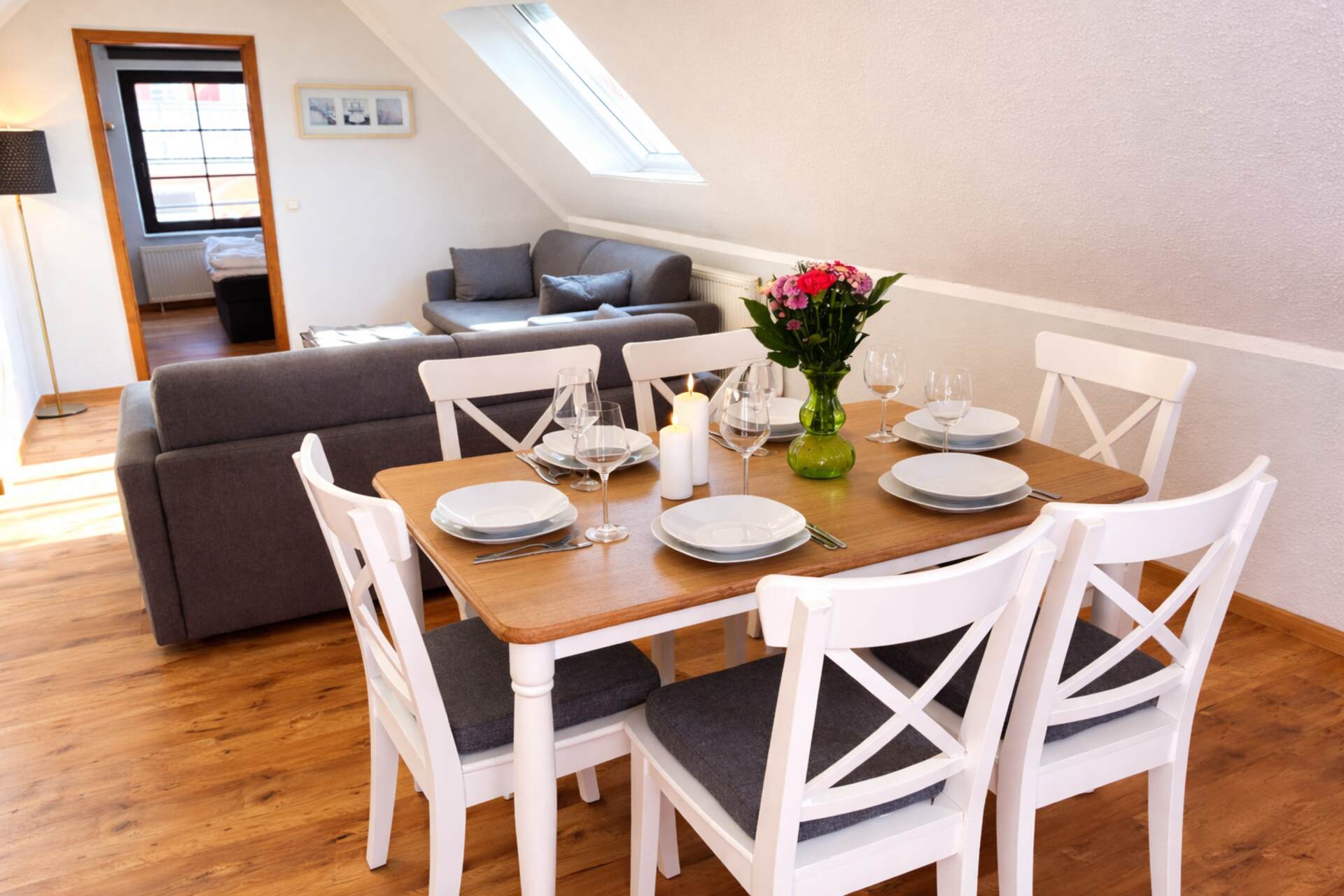 Esstisch mit Blumen und dahinter zwei Sofas