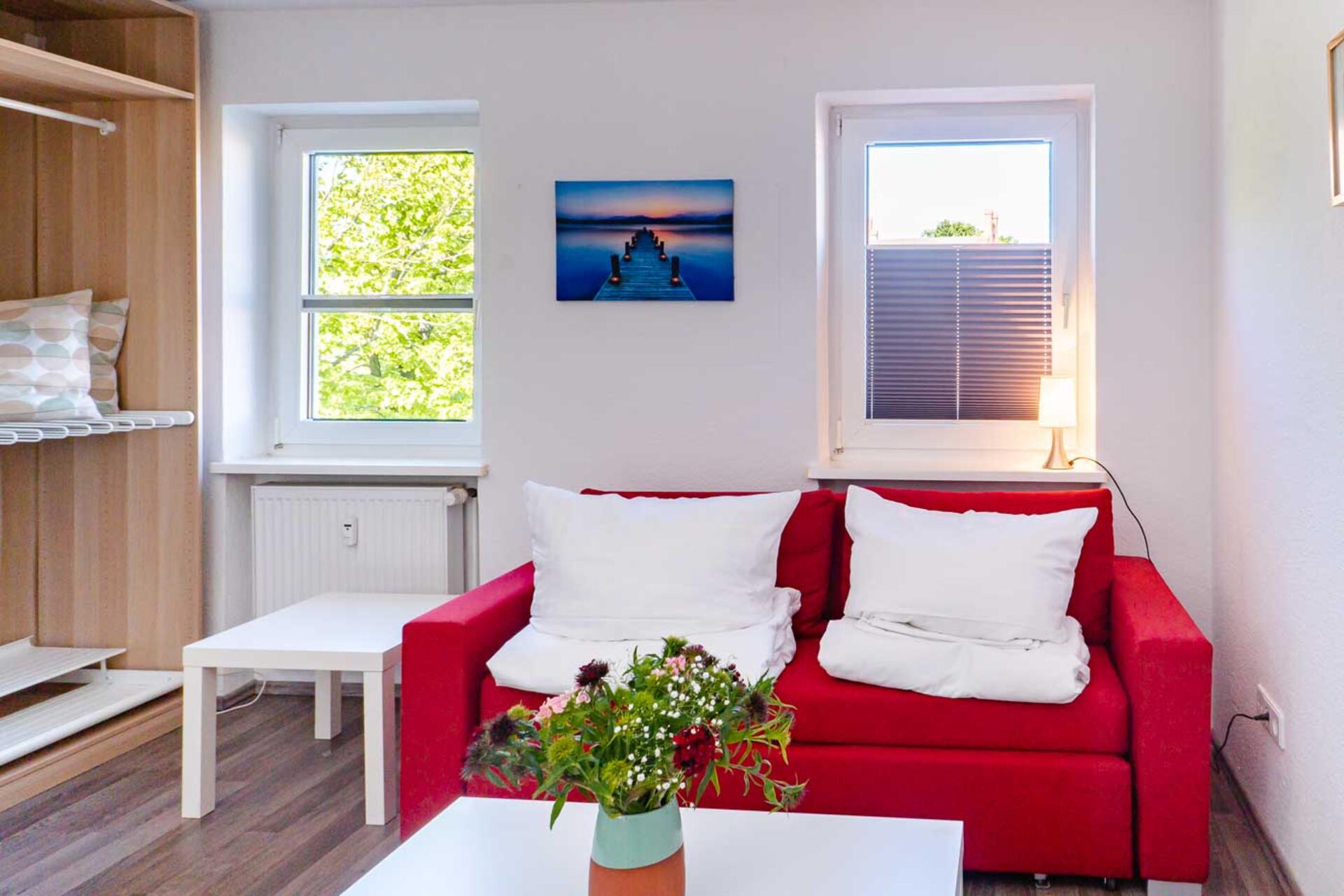 Rote Couch mit Bettdecken und Kissen