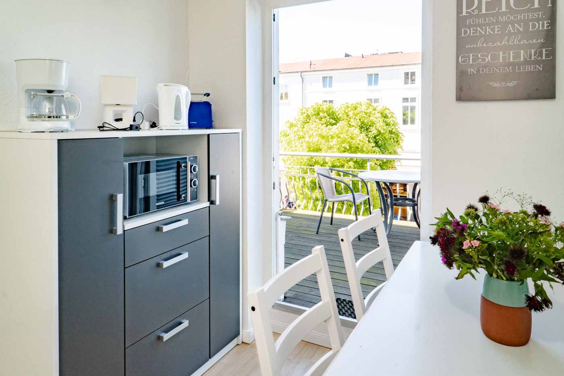 Esstisch mit Blick auf den Balkon mit Baeumen im Hintergrund