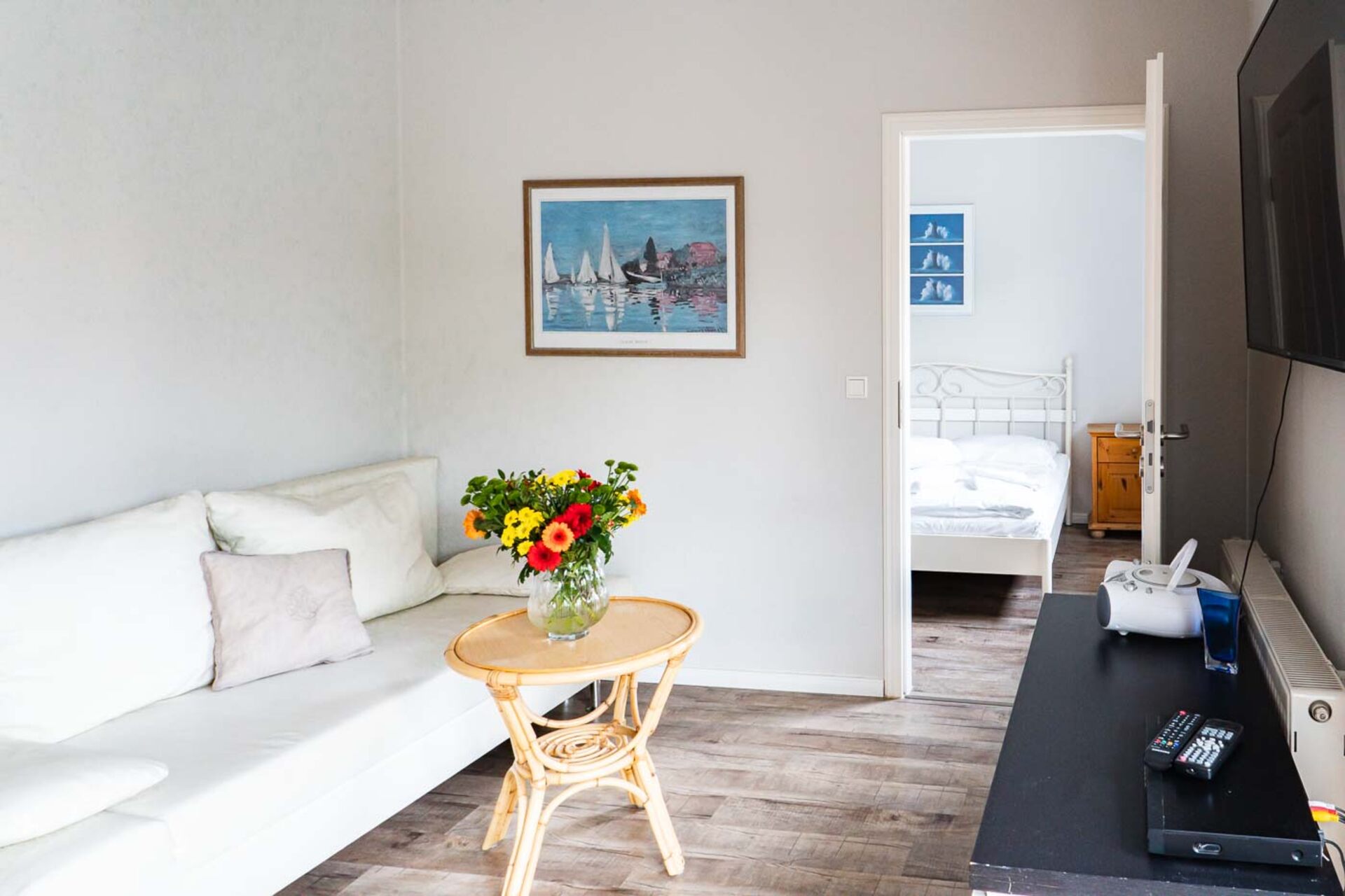 Wohnbereich mit Fernseher und Blick in das Schlafzimmer