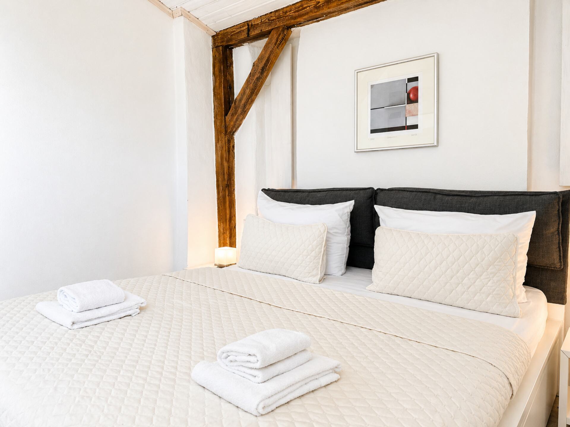 Bett im Schlafzimmer mit dekorativen Balken