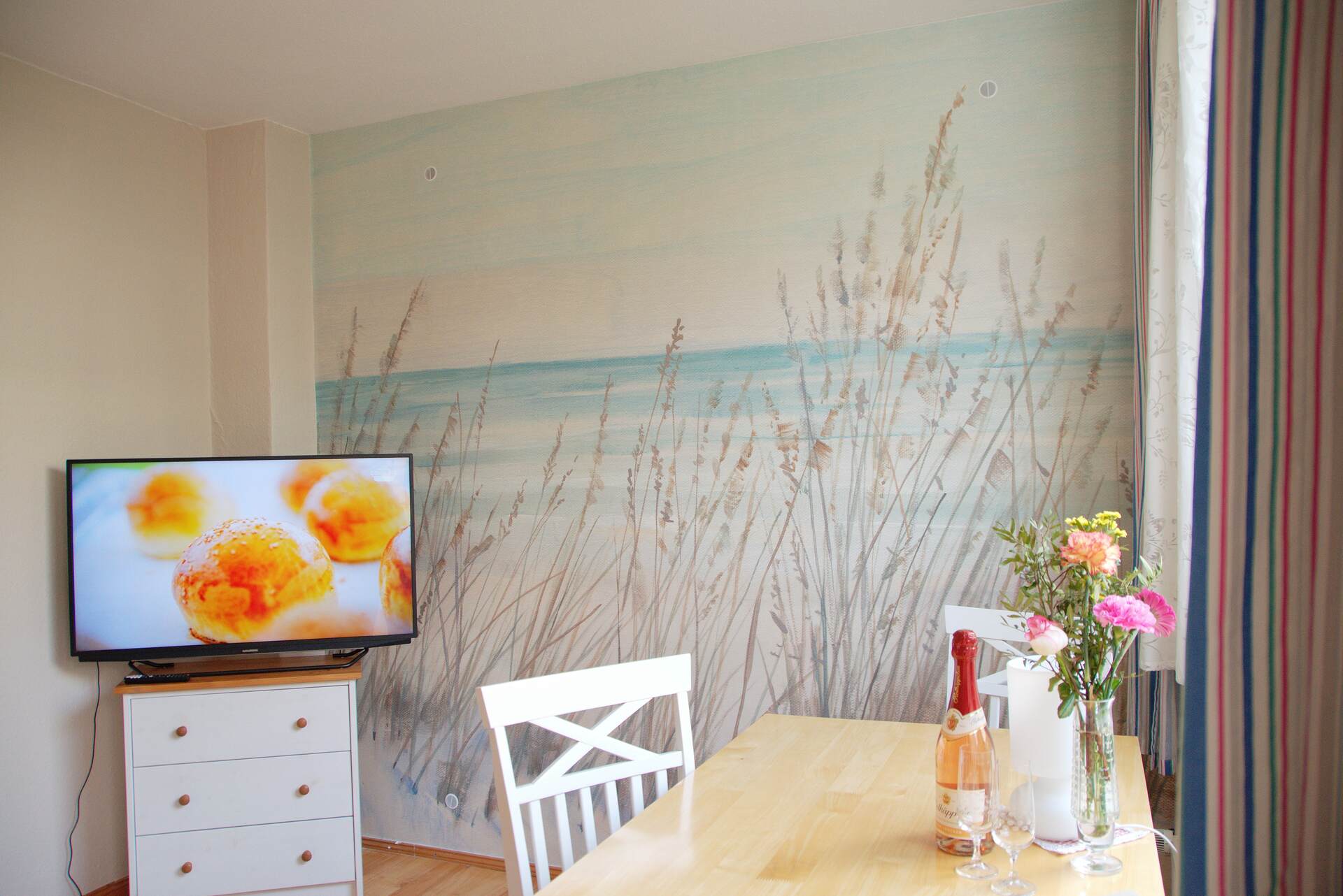 Esstisch mit Fernseher und Fototapete im Hintergrund
