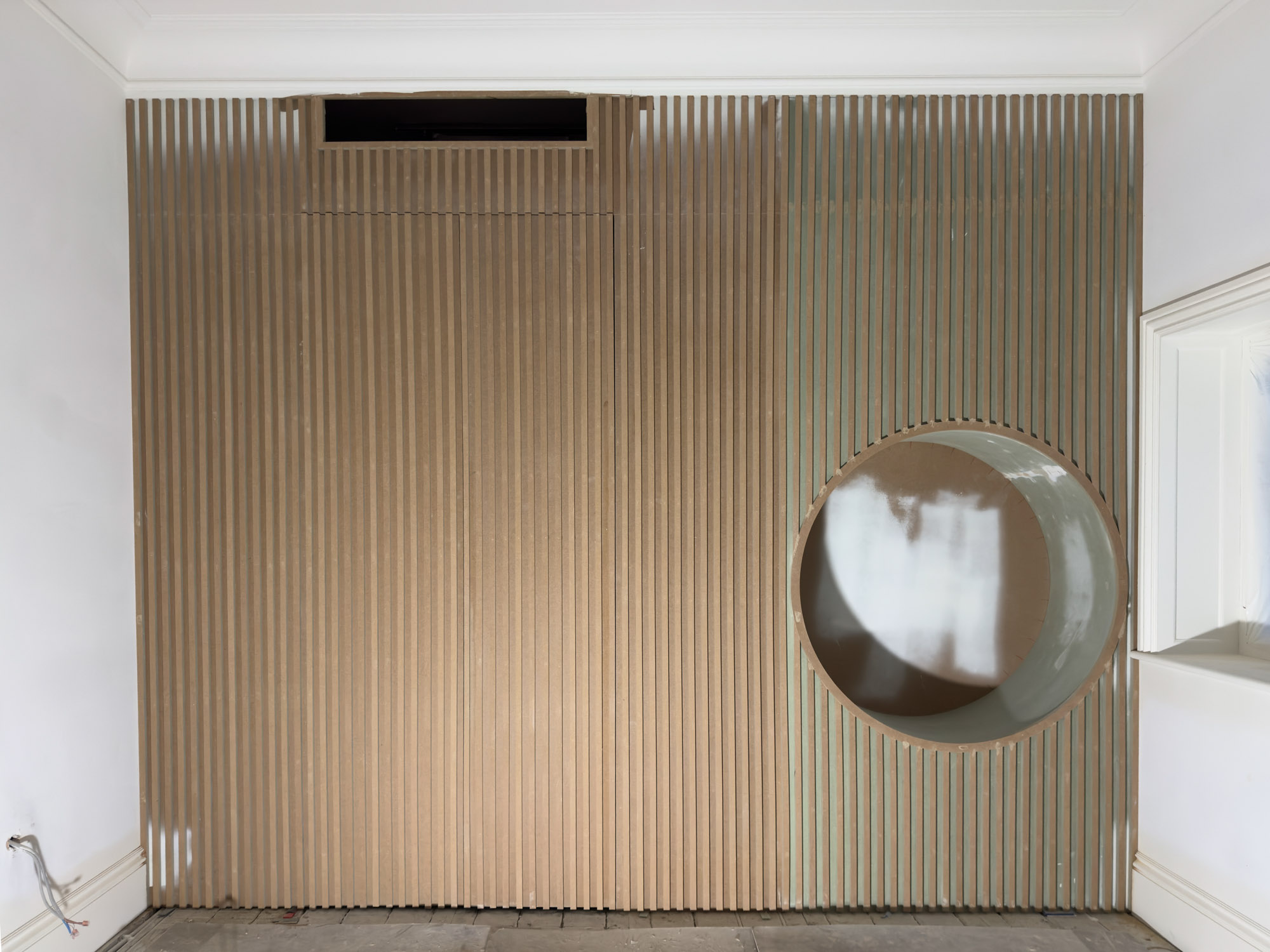 Unfinished built-in wooden shelving units flanking an empty fireplace space in a room under renovation.