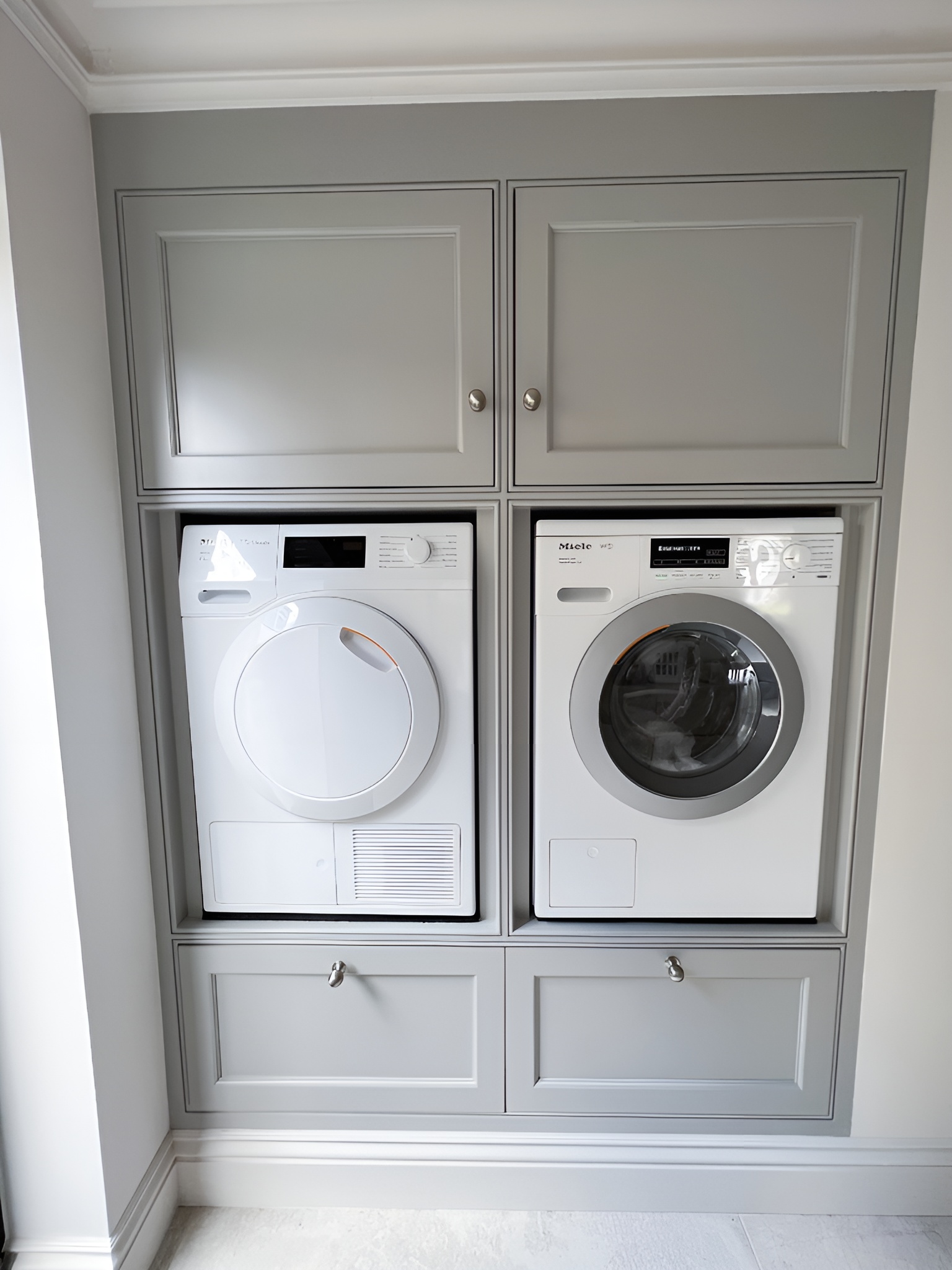 Built-in laundry unit with a white front-loading washing machine and dryer enclosed in gray cabinetry.