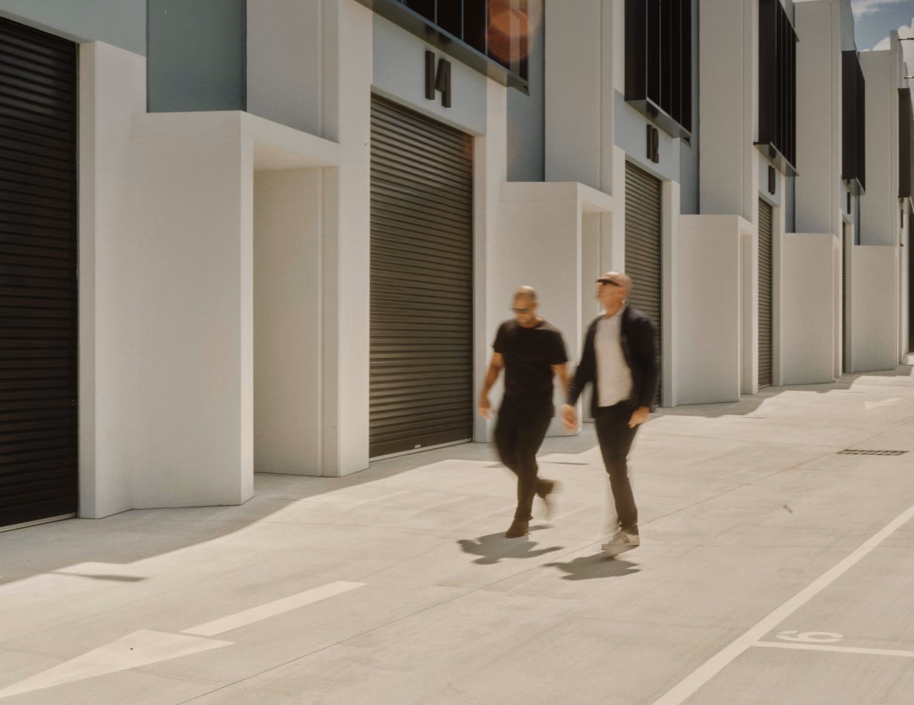 Two men walking past industrial warehouse units