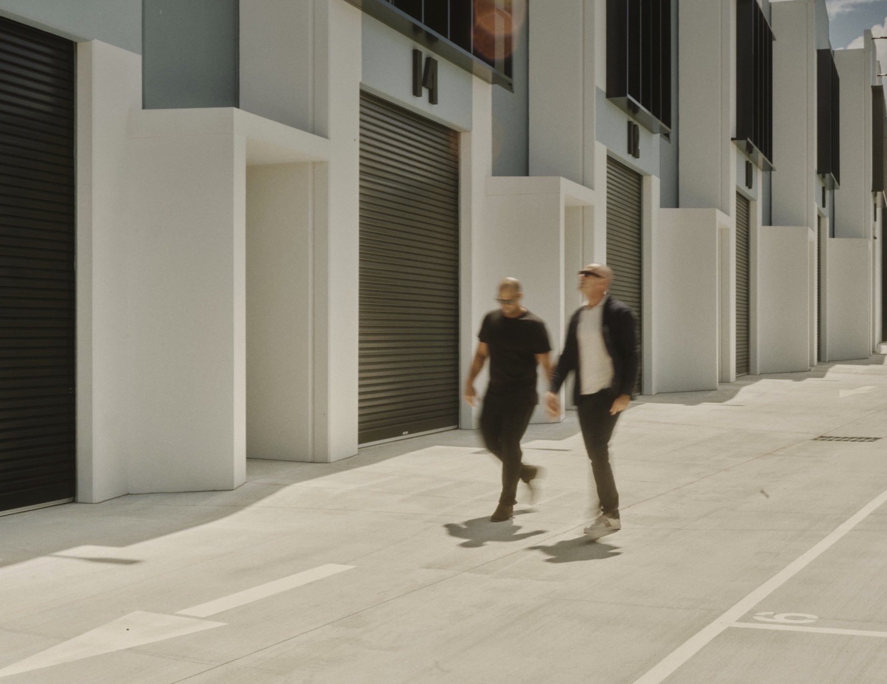 Two men walking past industrial warehouse units