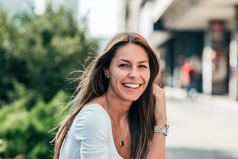 Smiling woman showing healthy white teeth outdoors