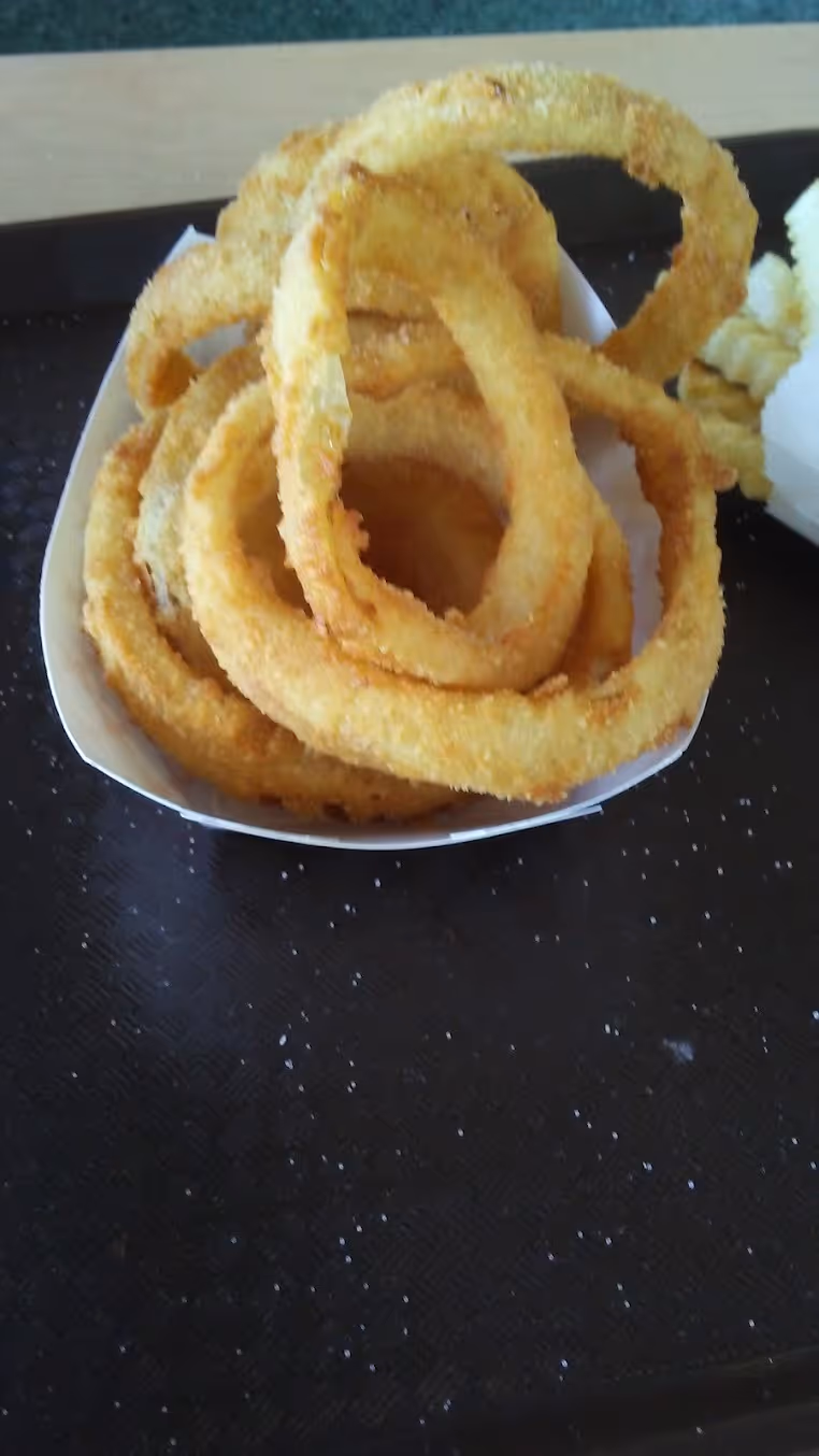 A white paper container with a fried onion ring in it.