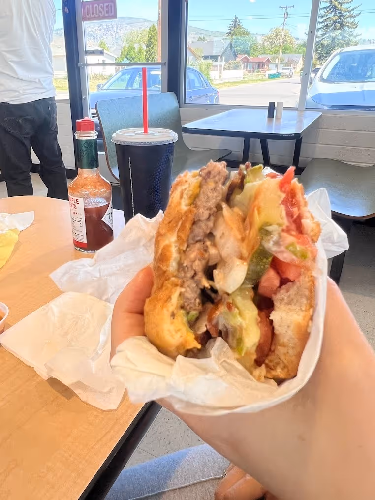 A person holding a sandwich with tomatoes and lettuce.