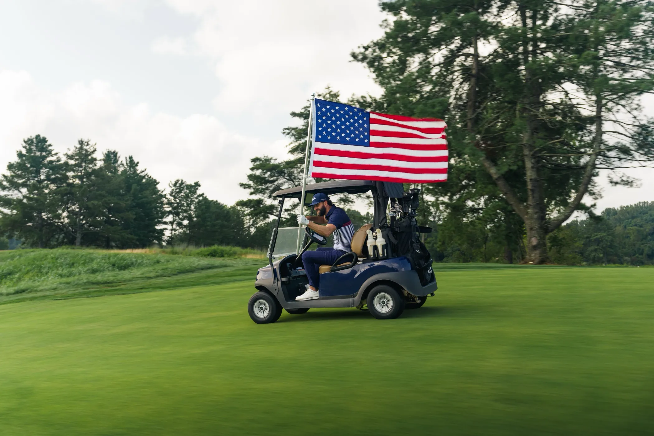 Golf cart flying an American flag on a fairway
