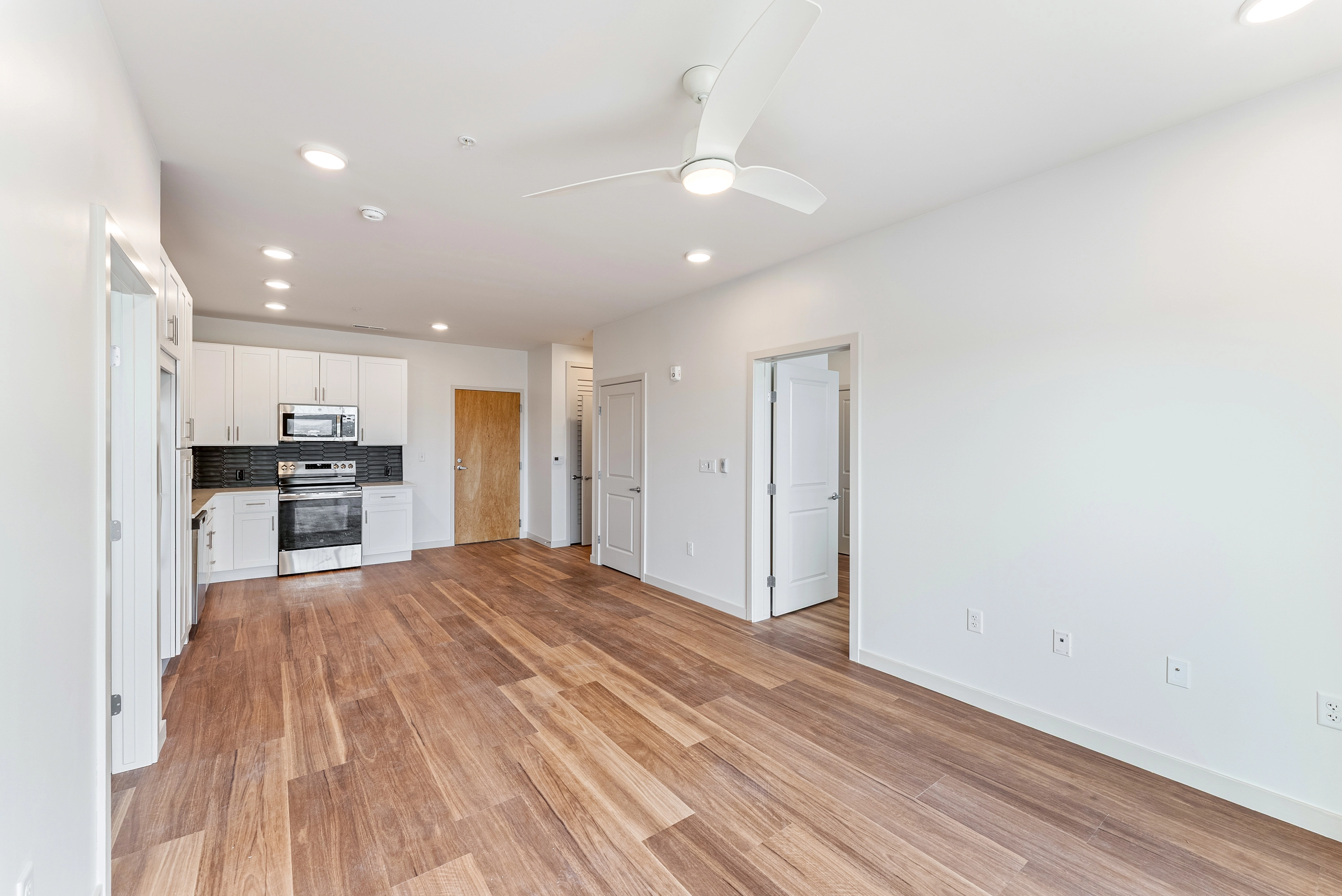 an open concept condo living room with a kitchen on the back left side