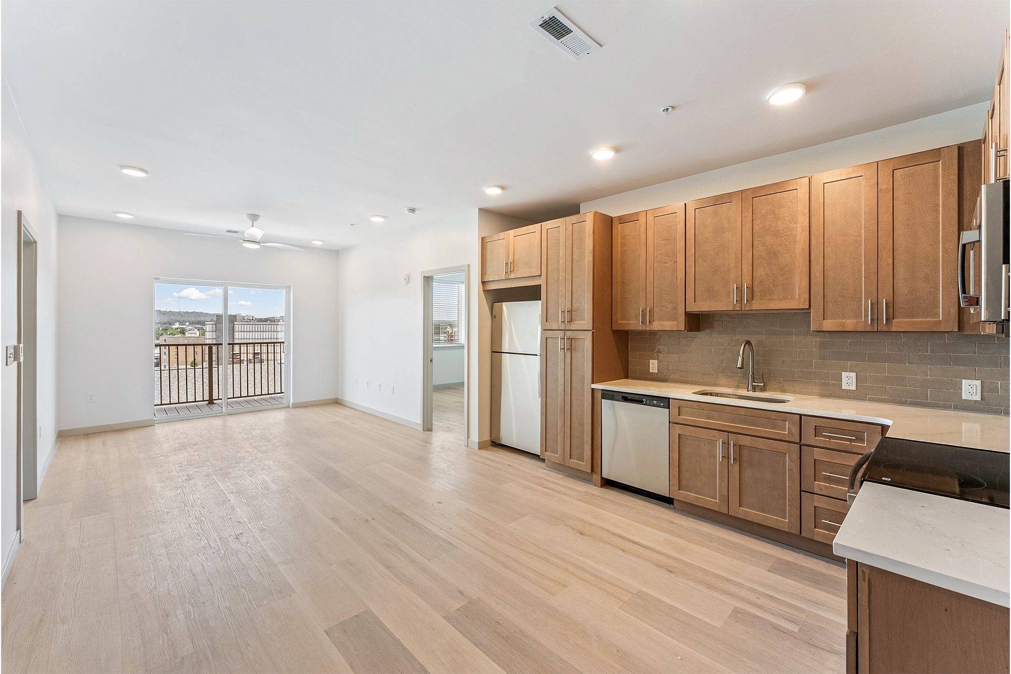 an open concept kitchen and living room with wooden floors in a room with a sliding glass door