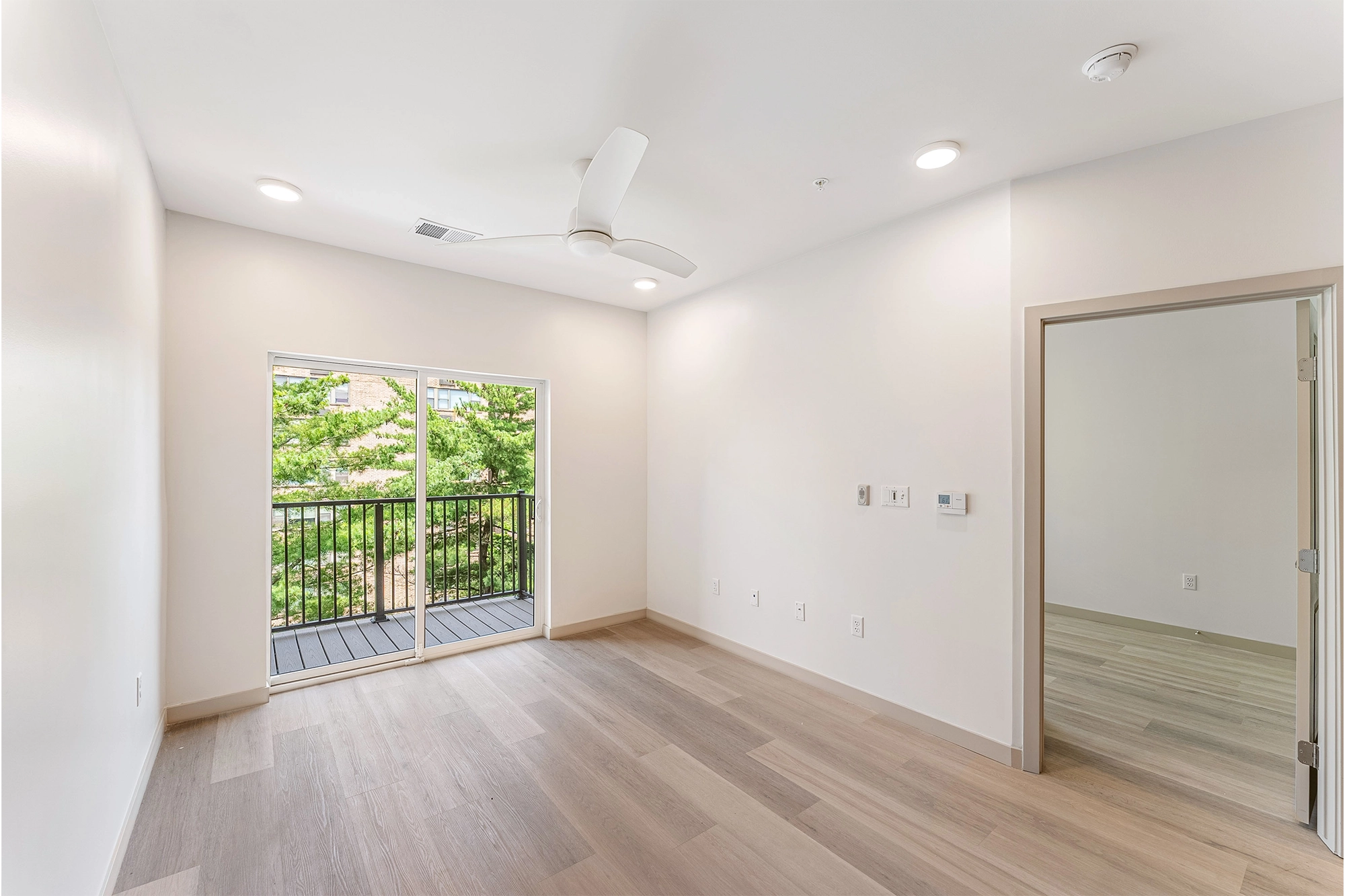 an open room with wooden floors and a sliding glass door that leads to balcony 