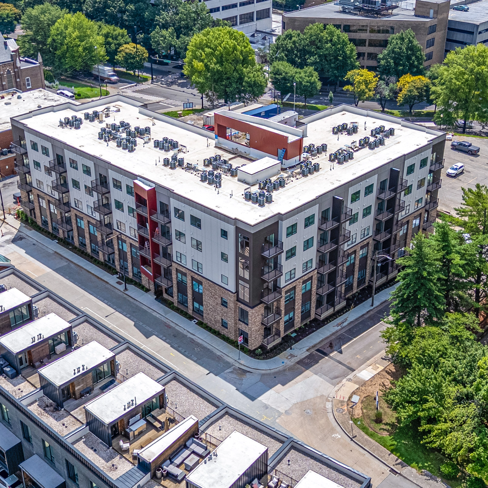 Modern City Summit apartment building with balconies and red architectural feature under clear blue sky.