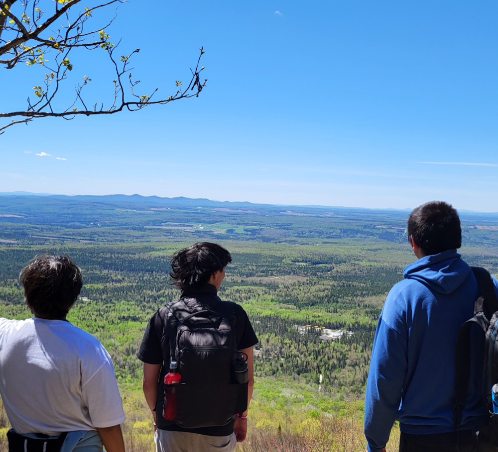 Trois jeunes en randonnée admirant un panorama en territoire