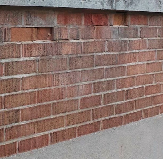 Spalling brick facade showing surface deterioration from moisture and freeze thaw damage