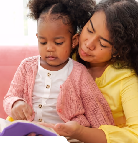 A young child and an adult looking at a book together