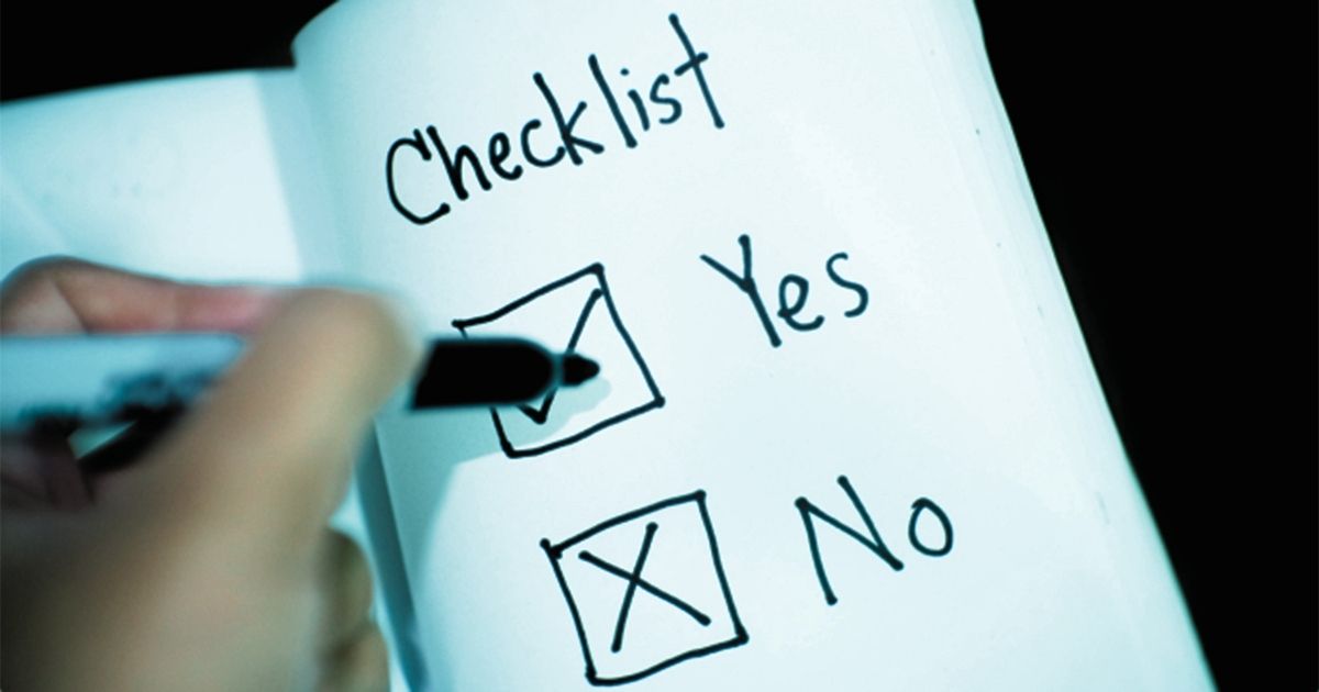 Hand holding a felt tipped pen above checkboxes labelled 'Yes and 'No' drawn in a notebook