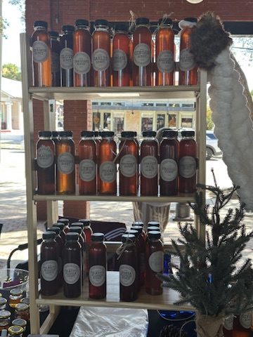 A market-stand shelf stocked with SEEDFOLKids honey