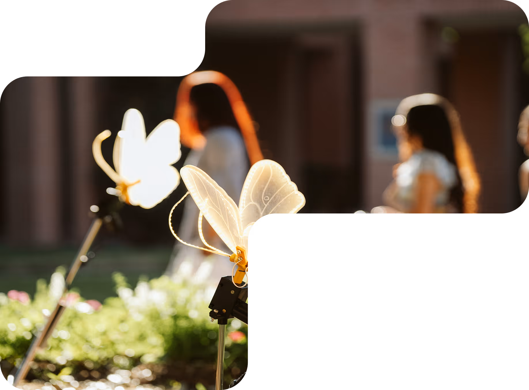 Glowing decorative butterfly lights on stakes with blurred people and flowers in the background.