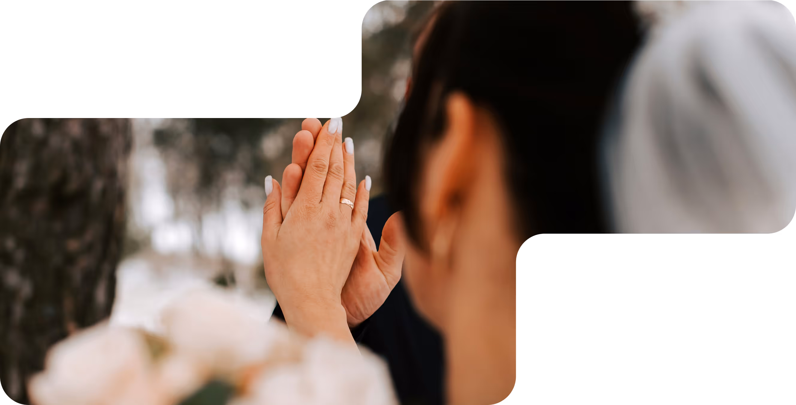 Close-up of two people touching hands with a visible wedding ring, blurred bouquet and background.