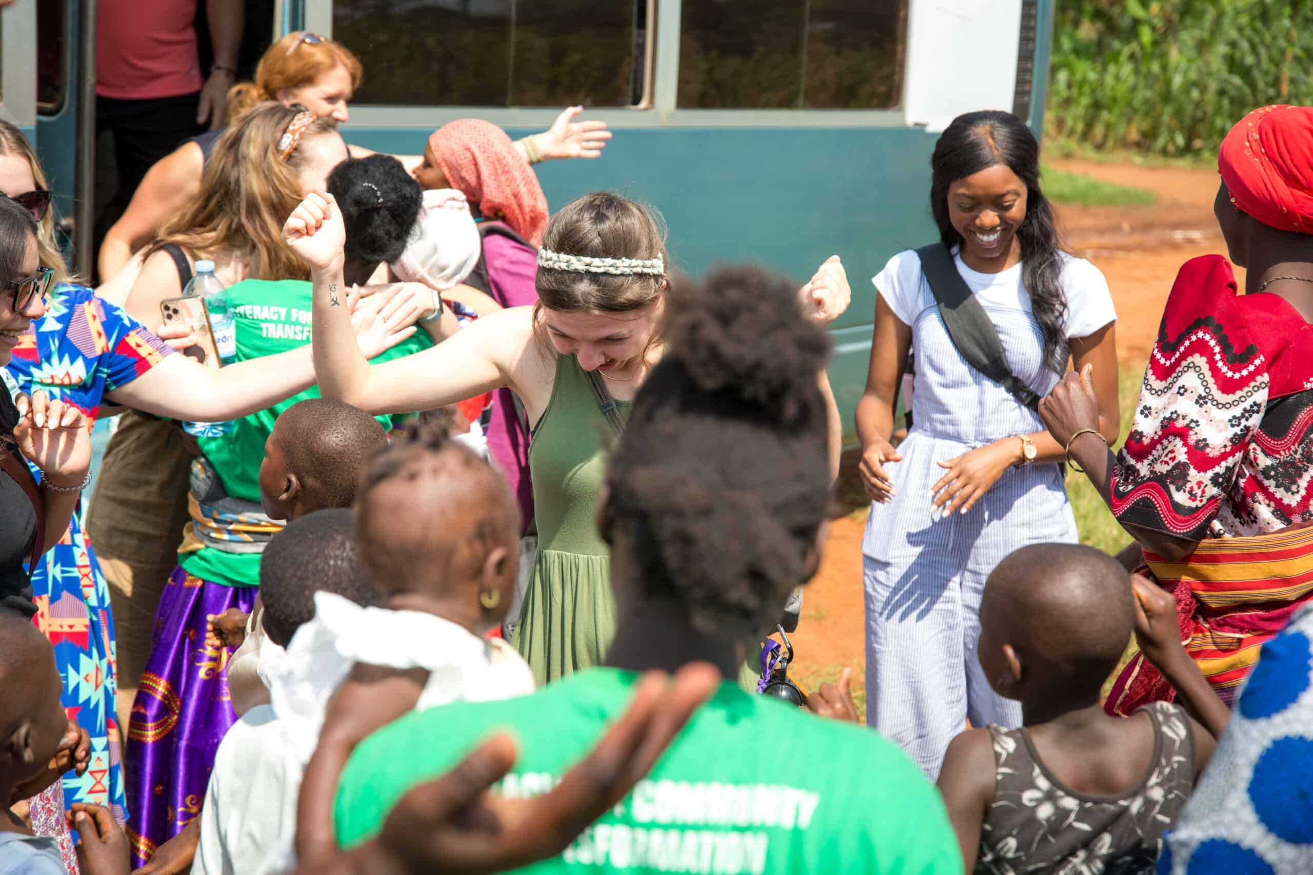 Group of smiling people, including children and adults, socializing outdoors near a bus.