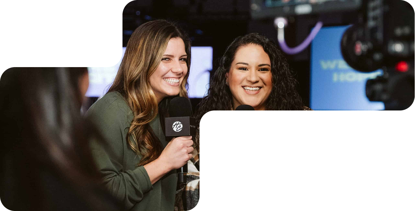 Two women smiling and holding microphones during a recording in a studio setting.