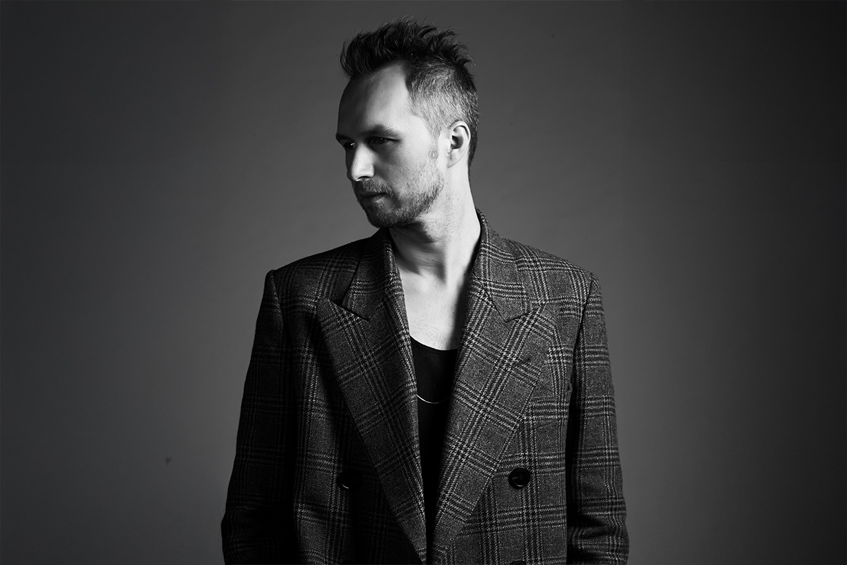 Toni Maticevski in a plaid double-breasted blazer looking left.
