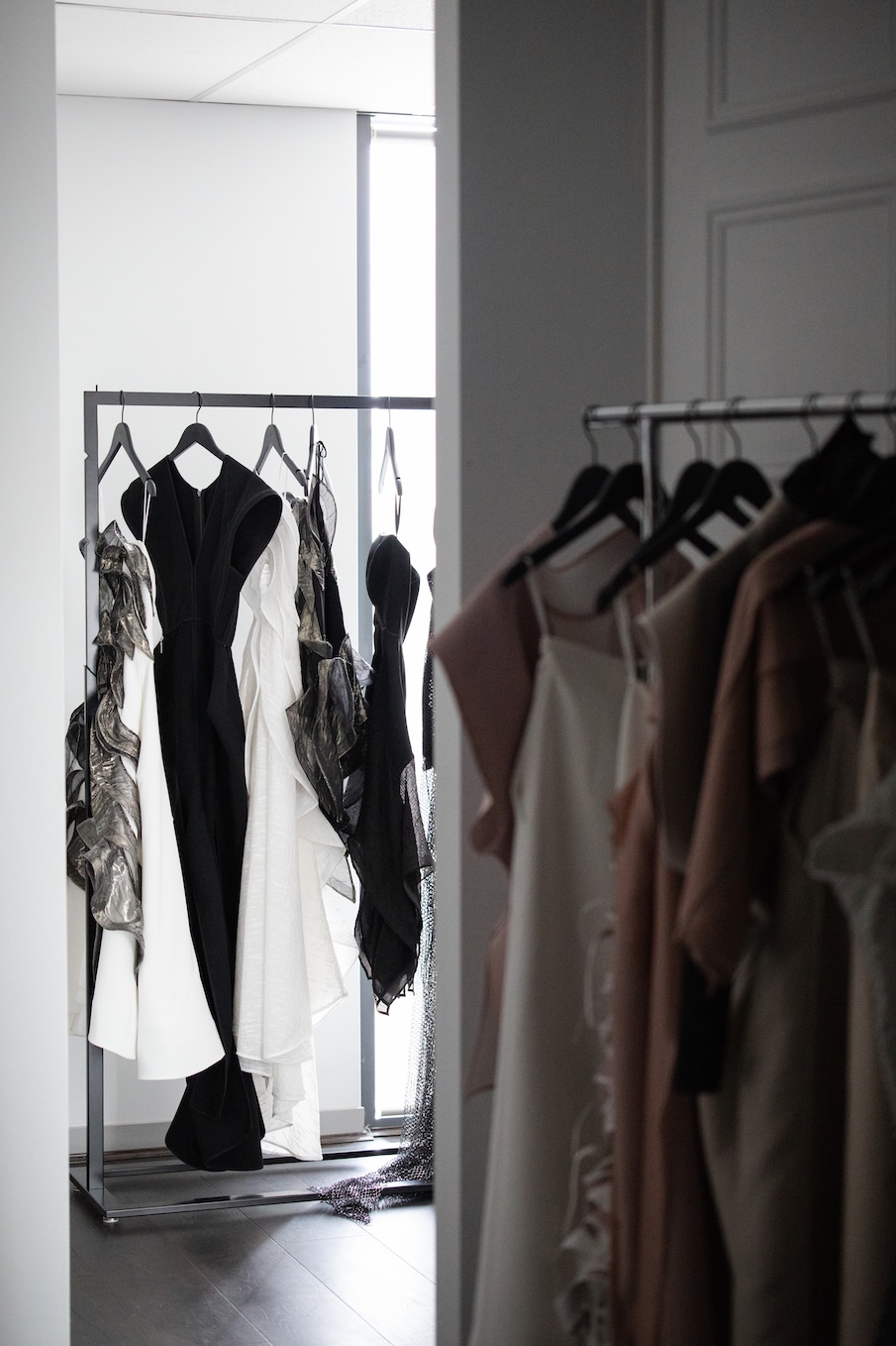 Modern clothing rack with black, white, and patterned dresses hanging in a softly lit room.
