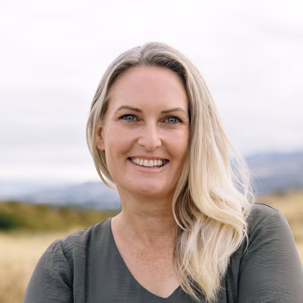 Headshot of Erin in a grey dress outdoors. 