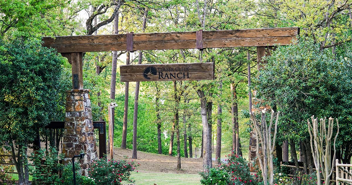 The Timber Creek Ranch entrance sign among the trees
