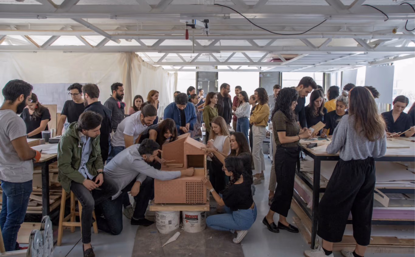 Colaboradores trabajando en un taller alrededor de una maqueta de una casa