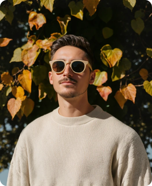 A man wearing sunglasses standing in front of a tree.