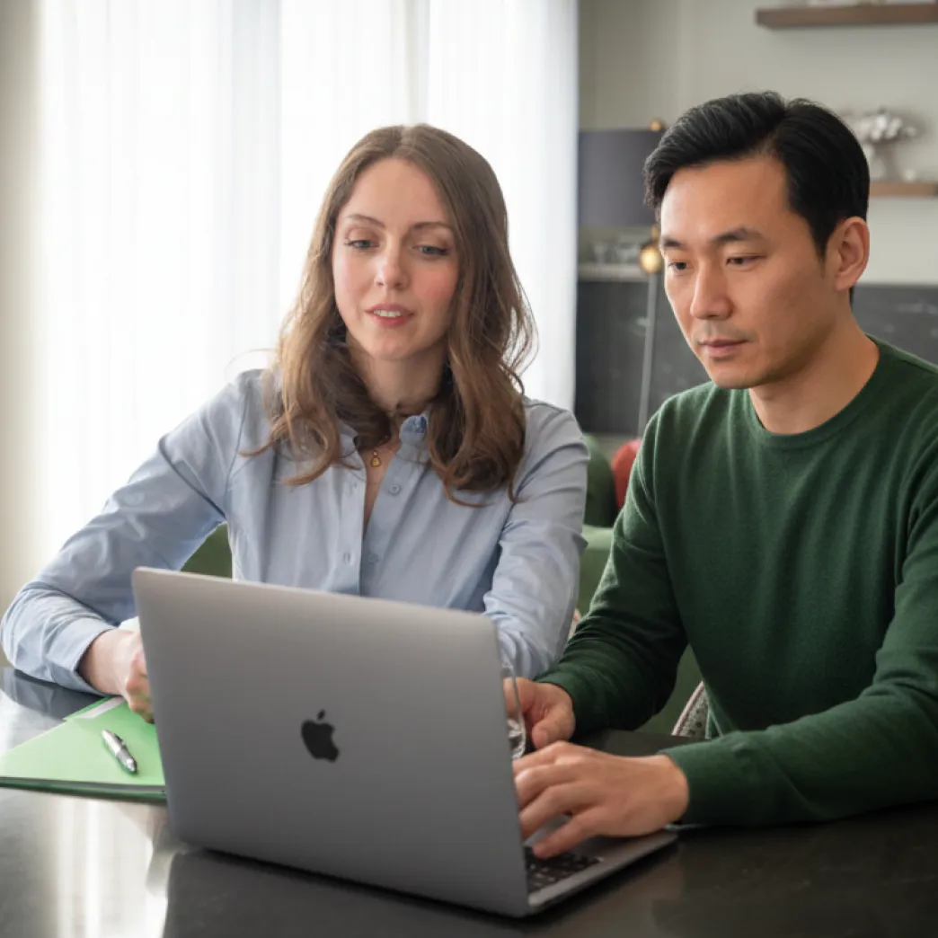 Two colleagues reviewing information together on a laptop in a bright, modern office.