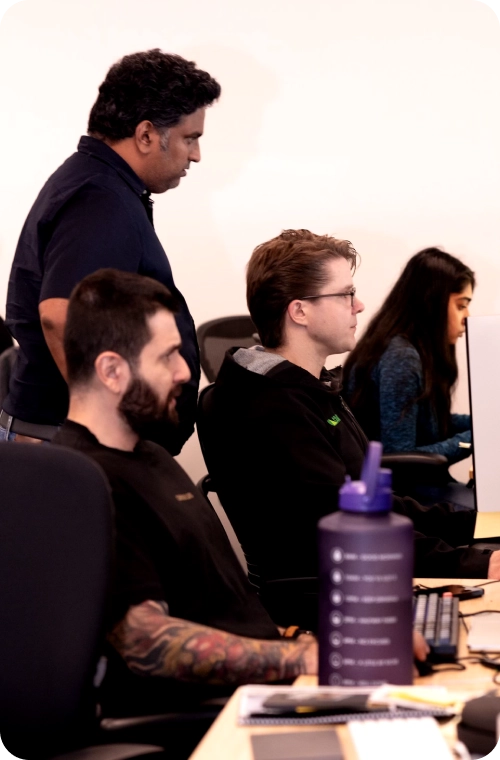 A diverse group of Coactive teme members seated at desks, focused on their computers in a collaborative workspace.